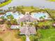 Aerial view of a resort-style pool and amenity center with palm trees and a lake in the background at 9437 Lemon Drop Loop, Sun City Center, FL 33573