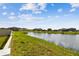 Manicured backyard features a tranquil pond view, grassy area, and white vinyl fence at 9437 Lemon Drop Loop, Sun City Center, FL 33573