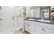 Bright bathroom with glass shower, double vanity, granite counters, white cabinets, and tile flooring at 9437 Lemon Drop Loop, Sun City Center, FL 33573