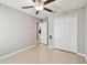 Neutral bedroom featuring a ceiling fan, closet doors, and neutral-colored tile floors at 9437 Lemon Drop Loop, Sun City Center, FL 33573