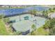 Aerial view of tennis courts with a shaded seating area and lush landscaping at 9437 Lemon Drop Loop, Sun City Center, FL 33573