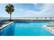 Sparkling outdoor pool with ocean view, surrounded by lounge chairs and a mature palm tree at 9980 Gulf Blvd # 408, Treasure Island, FL 33706