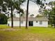 A view of the back of the home showing a modern white exterior, and large yard at 13186 Thrush St, Spring Hill, FL 34609