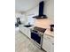 Modern kitchen featuring white cabinets, stainless steel appliances, marble-look countertops and an updated black range hood at 13186 Thrush St, Spring Hill, FL 34609
