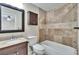 Bathroom featuring travertine tile, shower over tub, wood cabinets and granite vanity at 1331 Coolmont Dr, Brandon, FL 33511