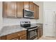 Modern kitchen featuring stainless steel appliances, granite countertops, and wooden cabinets at 13515 Palmera Vista Dr, Riverview, FL 33579