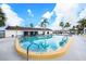 Enjoy this outdoor swimming pool with several palm trees, building and blue skies with clouds at 13710 Mission Oaks Blvd # 2A, Seminole, FL 33776