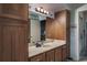 Bathroom with wood cabinets, a marble counter, mirror, and decorative light fixtures at 1510 Palmer Ct, Palm Harbor, FL 34685
