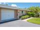 Villa with an attached garage featuring a well-manicured lawn and lush landscaping at 1510 Palmer Ct, Palm Harbor, FL 34685