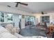 Bright sunroom with stone floors, ceiling fans, seating arrangements, and sliding doors to the outside at 1510 Palmer Ct, Palm Harbor, FL 34685