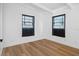 Bright bedroom featuring hardwood floors, two windows, and white walls and trim at 1707 Windsor Way, Tampa, FL 33619