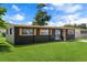 Beautifully renovated single story home with dark exterior, decorative shutters, and a lush front yard at 1707 Windsor Way, Tampa, FL 33619