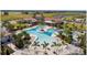 Aerial view of resort-style pool, palm trees, cabanas and lush landscaping, surrounded by clubhouse and residences at 17140 Holly Well Ave, Wimauma, FL 33598