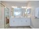 Bathroom with double sinks, granite countertops, white cabinets, and tiled shower at 17140 Holly Well Ave, Wimauma, FL 33598