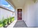 Covered front porch with brick flooring and a dark wood front door, offering curb appeal at 17140 Holly Well Ave, Wimauma, FL 33598