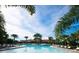 Large community swimming pool surrounded by palm trees and lounge chairs under a sunny sky at 17140 Holly Well Ave, Wimauma, FL 33598