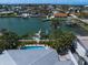 An aerial view showcases a backyard pool, dock, and canal-front property with palm trees at 202 Howard Dr, Belleair Beach, FL 33786