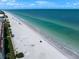 Gorgeous white sand beach and crystal clear ocean with beach goers enjoying a perfect Florida day at 202 Howard Dr, Belleair Beach, FL 33786