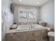 Bathroom with a built-in tub under a window and neutral tiling at 202 Howard Dr, Belleair Beach, FL 33786