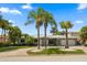 Charming single-story home featuring lush landscaping and a circular driveway lined with palm trees at 202 Howard Dr, Belleair Beach, FL 33786