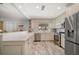 Bright kitchen featuring stainless steel appliances, light wood floors, and a breakfast bar overlooking the living area at 202 Howard Dr, Belleair Beach, FL 33786