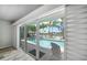 View of outdoor pool, palm trees and waterfront canal seen through large glass doors at 202 Howard Dr, Belleair Beach, FL 33786