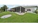Backyard showcases a screened lanai surrounded by verdant lawn and decorative landscaping at 2306 Emerald Lake Dr, Sun City Center, FL 33573