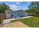 The light blue home features a spacious, grassy backyard with a concrete patio, offering a tranquil outdoor space at 2692 Cedarbrooke Dr, Palm Harbor, FL 34684