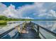 Picturesque wooden dock stretching out into the tranquil lake under a stunning blue sky with puffy white clouds at 2692 Cedarbrooke Dr, Palm Harbor, FL 34684