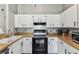 Efficient kitchen featuring white cabinets, wood-look countertops, and black appliances at 2692 Cedarbrooke Dr, Palm Harbor, FL 34684