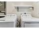 Bright laundry room featuring white appliances and a floating shelf for storage at 2692 Cedarbrooke Dr, Palm Harbor, FL 34684