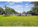 Lush community playground with colorful play structures, surrounded by well-kept green grass and mature palm trees at 2692 Cedarbrooke Dr, Palm Harbor, FL 34684