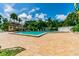 Community pool and clubhouse bordered by palm trees, fenced, with a seating area and well-maintained pool deck at 2692 Cedarbrooke Dr, Palm Harbor, FL 34684