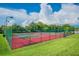 Exterior shot of fenced tennis courts on a sunny day, showcasing the recreational amenities offered within the community at 2692 Cedarbrooke Dr, Palm Harbor, FL 34684