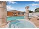 Inviting hot tub with stone pillars in a beautiful backyard setting, with a fenced-in pool area and orange home at 30703 San An Rd, San Antonio, FL 33576