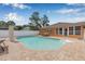 Backyard pool with surrounding brick pavers, ideal for outdoor enjoyment and relaxation; an orange house sits behind it at 30703 San An Rd, San Antonio, FL 33576