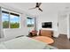 Bright bedroom featuring large windows with lush tree view, ceiling fan, television, and wood floors at 3100 W Paul Ave # 14, Tampa, FL 33611