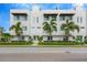 Modern townhome featuring a clean, minimalist design, complemented by lush palm trees and manicured landscaping at 3100 W Paul Ave # 14, Tampa, FL 33611