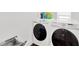 Modern laundry room features white, front-load washer and dryer with storage at 3100 W Paul Ave # 14, Tampa, FL 33611