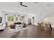 Bright, open living room with dark wood floors, large windows, and modern furnishings leading to the dining area and stairs at 3100 W Paul Ave # 14, Tampa, FL 33611