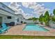 Relaxing backyard pool area with brick pavers, comfortable seating, outdoor grill, and lush tropical landscaping at 314 Blackrock Ln, Apollo Beach, FL 33572