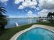 Backyard pool with waterfront access, pier, and dock, against a cloudy blue sky at 413 Midway Is, Clearwater Beach, FL 33767