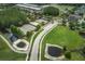 Aerial view of community amenities including tennis courts, a parking lot, and green spaces near residential area at 4222 Glade Wood Loop, New Port Richey, FL 34655