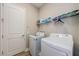 Well-lit laundry room with washer, dryer, storage shelf, and convenient access to the home at 4222 Glade Wood Loop, New Port Richey, FL 34655