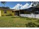 Spacious backyard with a screened-in pool, yellow house, and mature trees at 4407 Westwood Dr, Holiday, FL 34691