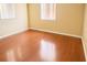 A vacant bedroom with wood floor and two windows at 4407 Westwood Dr, Holiday, FL 34691