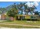 Charming yellow home with a well-manicured lawn and mature trees in the front yard at 4407 Westwood Dr, Holiday, FL 34691