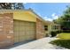 Tan garage door of yellow house with stacked stone facade and sunny skies at 4407 Westwood Dr, Holiday, FL 34691