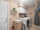 Functional laundry room with white washer and dryer and convenient storage options and a utility sink at 4610 Westford Cir, Tampa, FL 33618