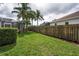 A wide yard with grass, a fence, and palm trees at 4736 Stonebriar Dr, Oldsmar, FL 34677
